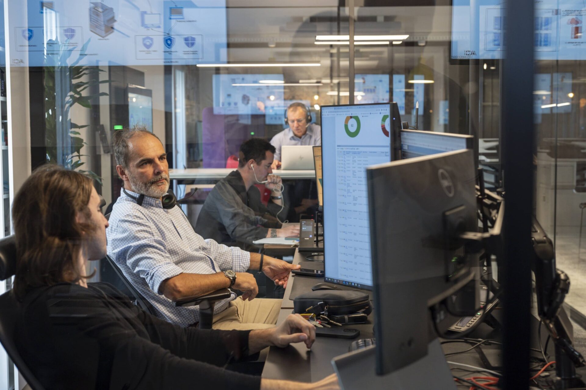 Équipe IT supervisant des infrastructures informatiques sur écrans de monitoring