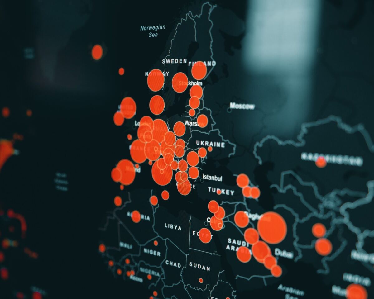 arrière plan noir avec une carte du monde sur laquelle figurent des points rouges plus ou moins gros représentant des zones infectées