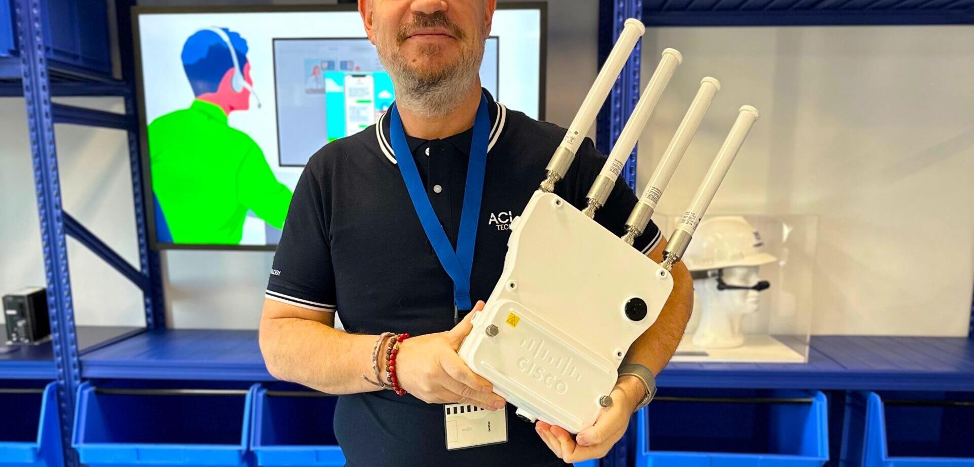 Ingénieur système et réseau d'ACI Technology avec une borne wifi pour entreprise