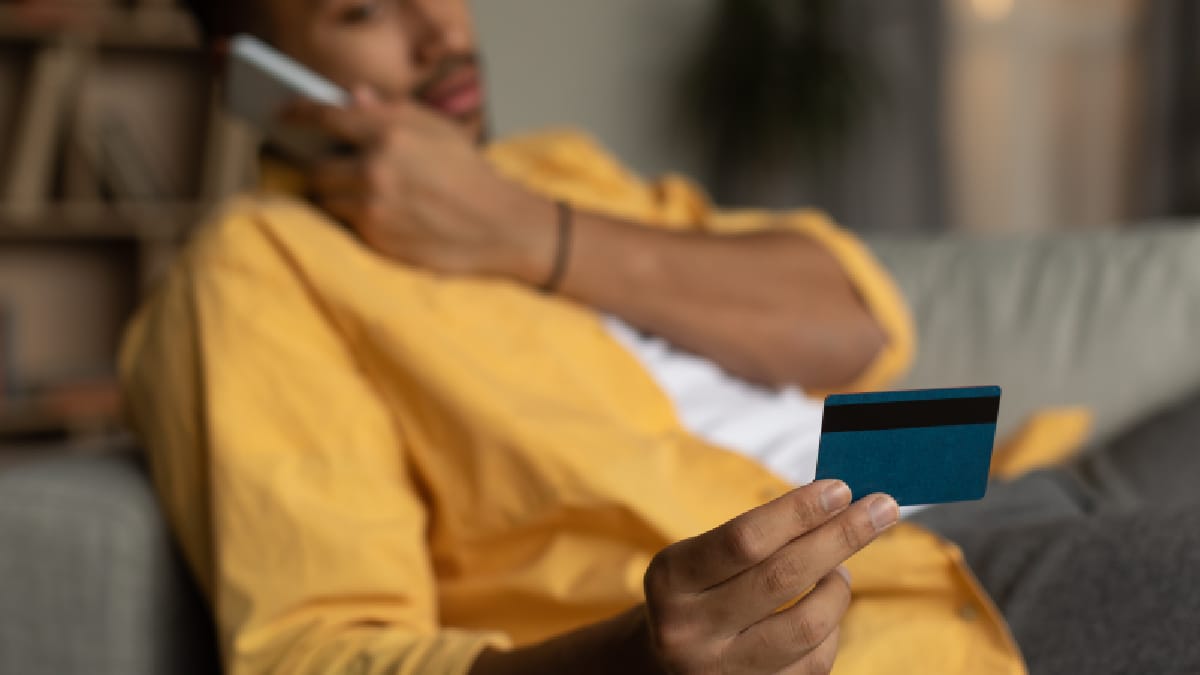 personne tenant une carte bancaire tout en passant un appel téléphonique